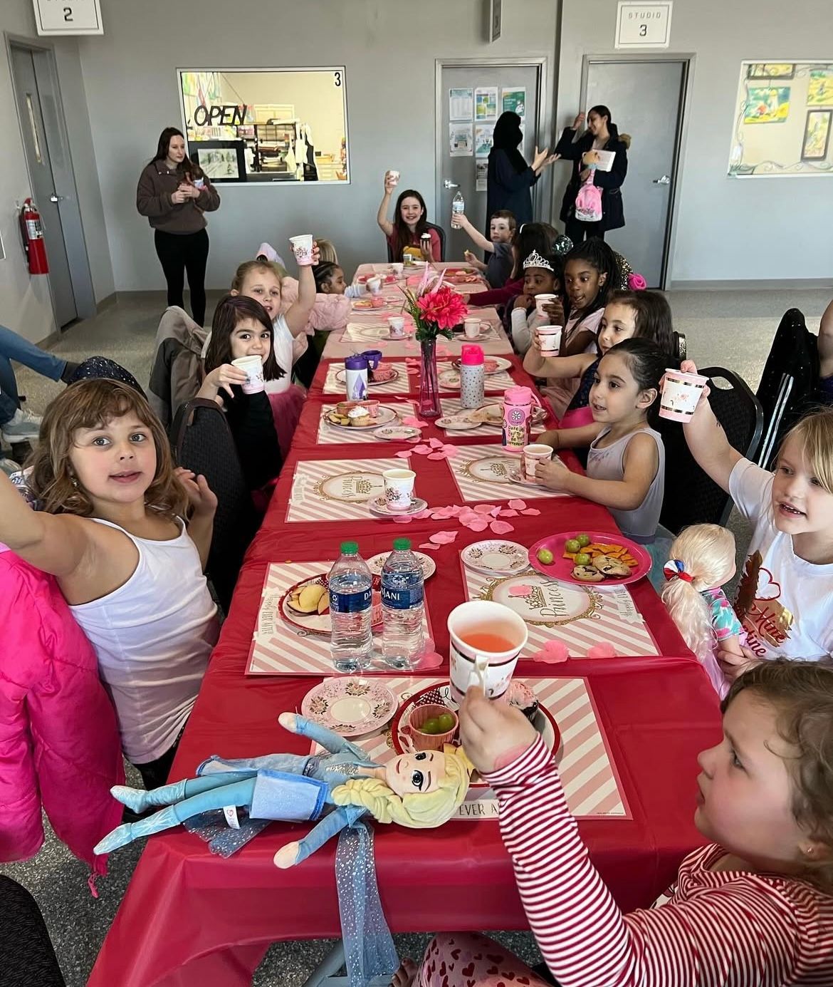 A group of children are sitting at a long table eating food.