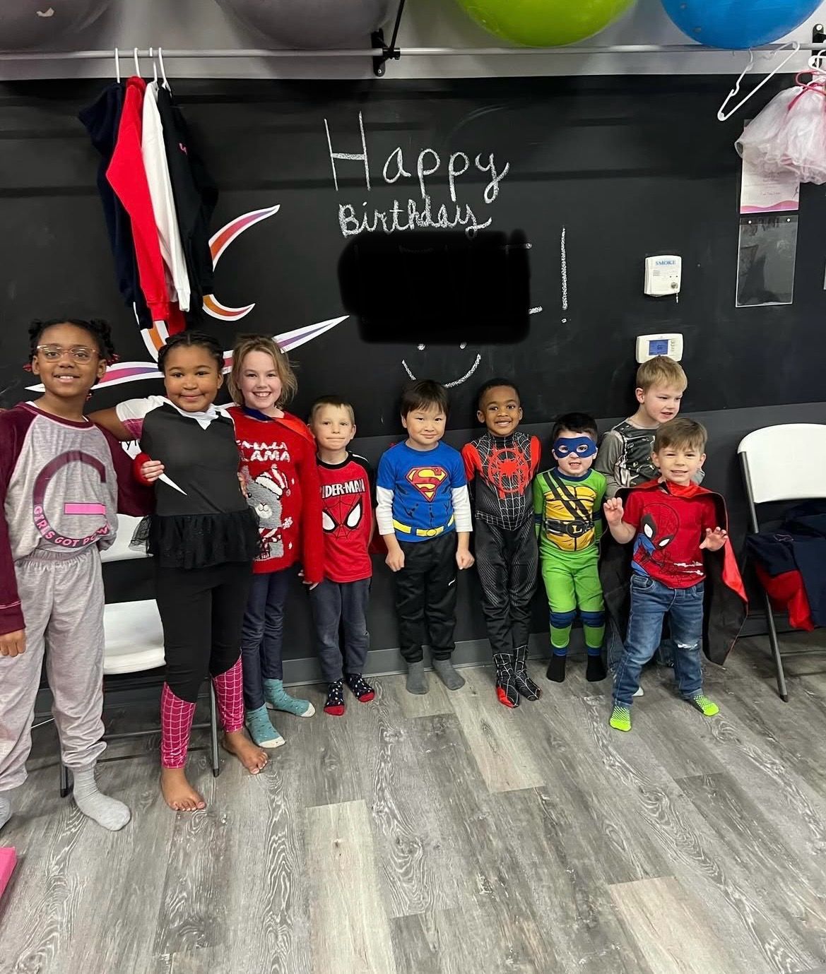 A group of children dressed in superhero costumes are posing for a picture.