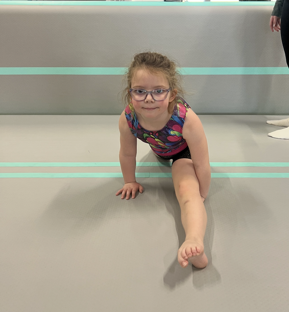 A little girl wearing glasses is crawling on the floor