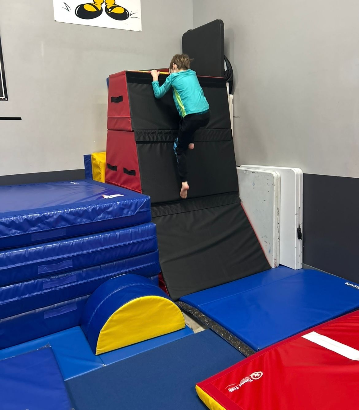 A little girl is climbing a wall in a gym