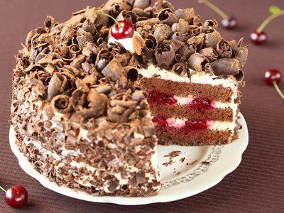 A chocolate cake with cream and cherry filling, and chocolate curls on top