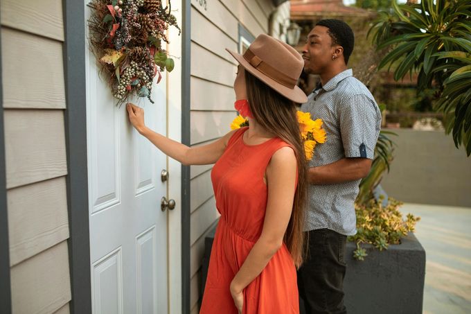 A man is kissing a woman on the cheek while she knocks on the door.