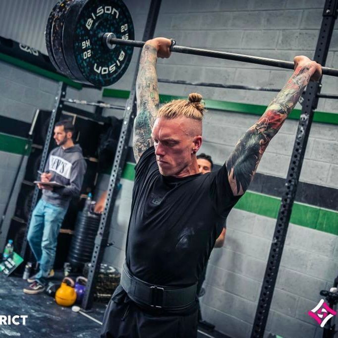 A man is lifting a barbell in a gym that says bison on it