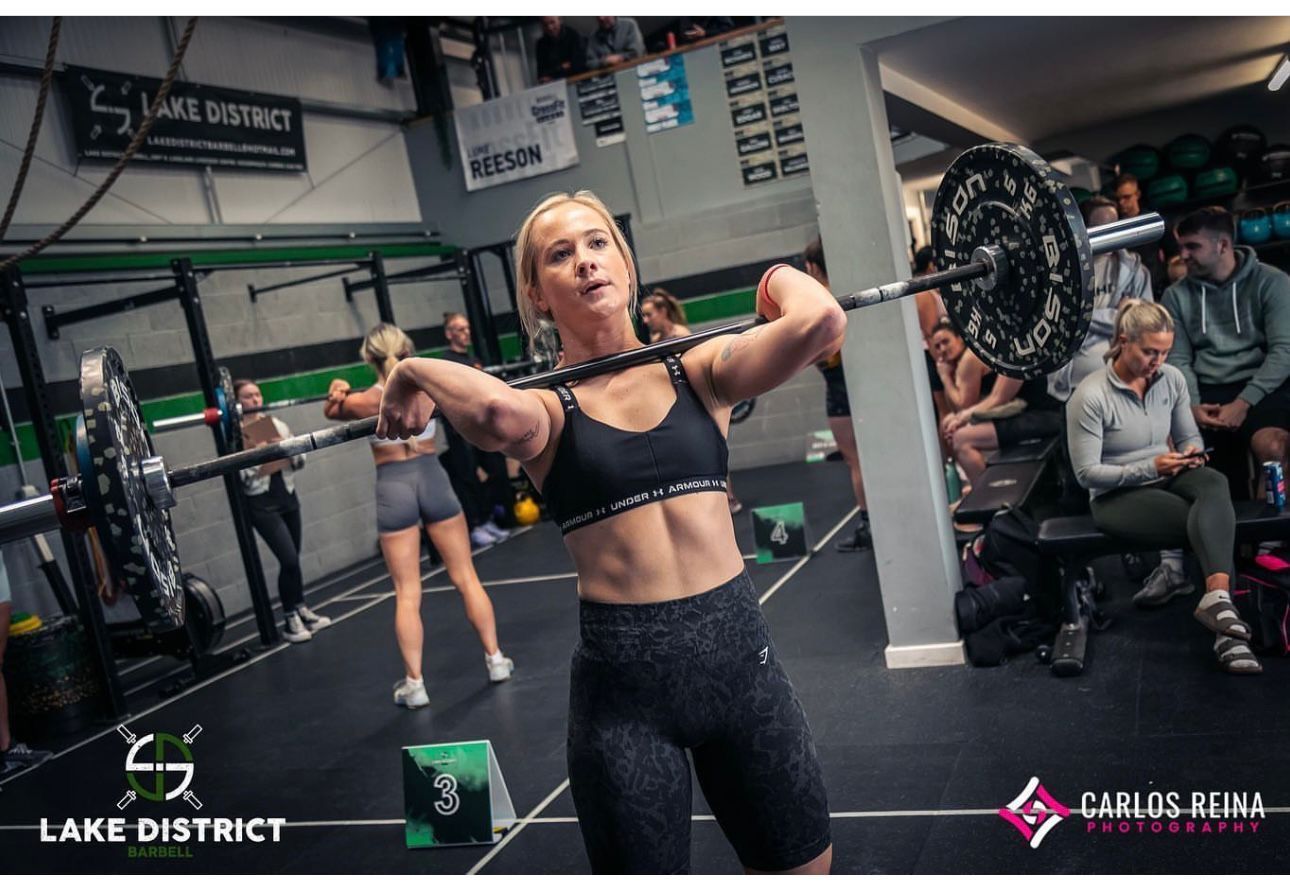 A woman is lifting a barbell in a gym.