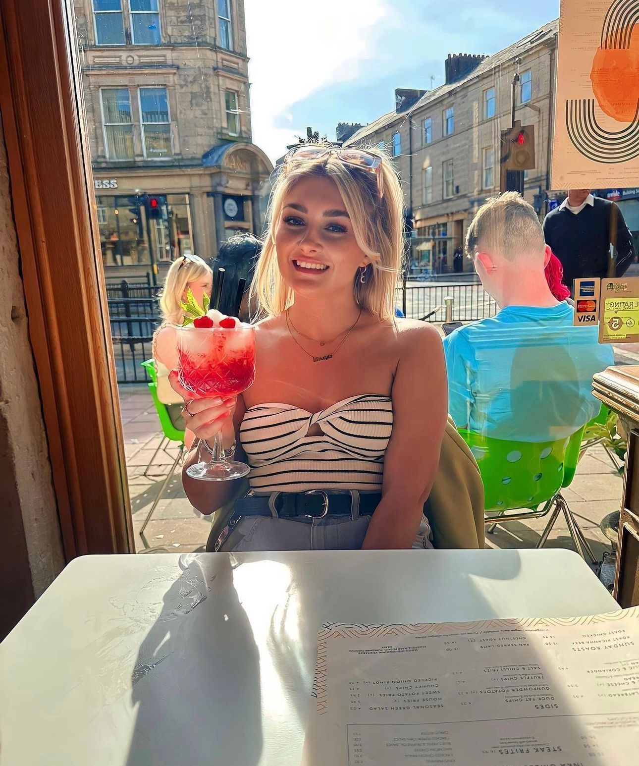 A woman is sitting at a table holding a glass of ice cream.