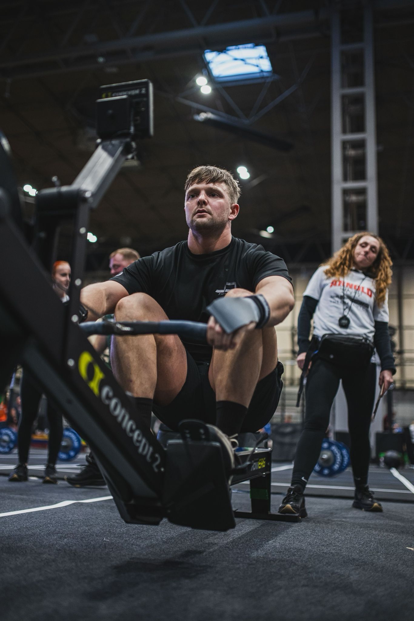 A man is sitting on a rowing machine in a gym.