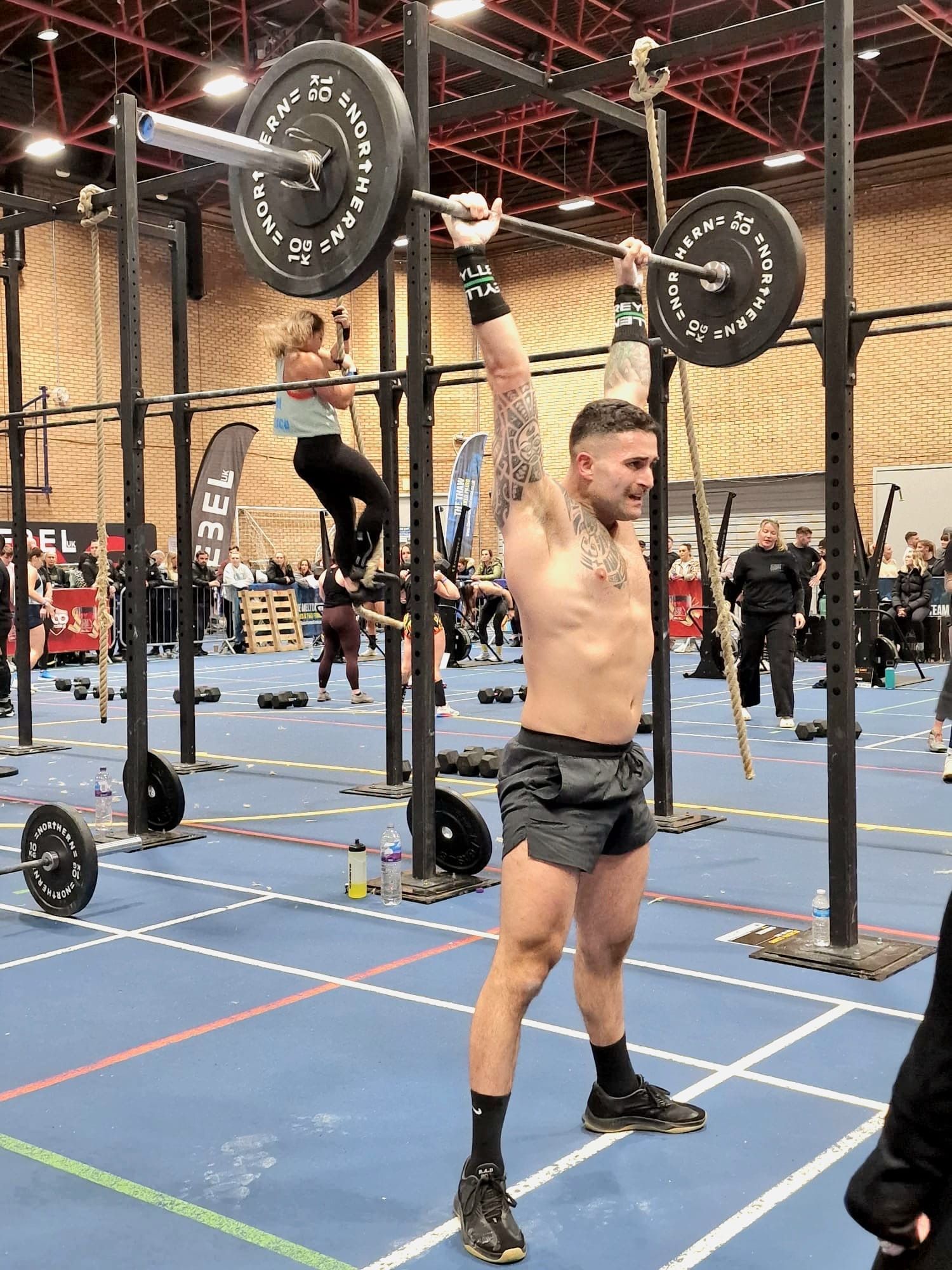 A man is lifting a barbell over his head in a gym.