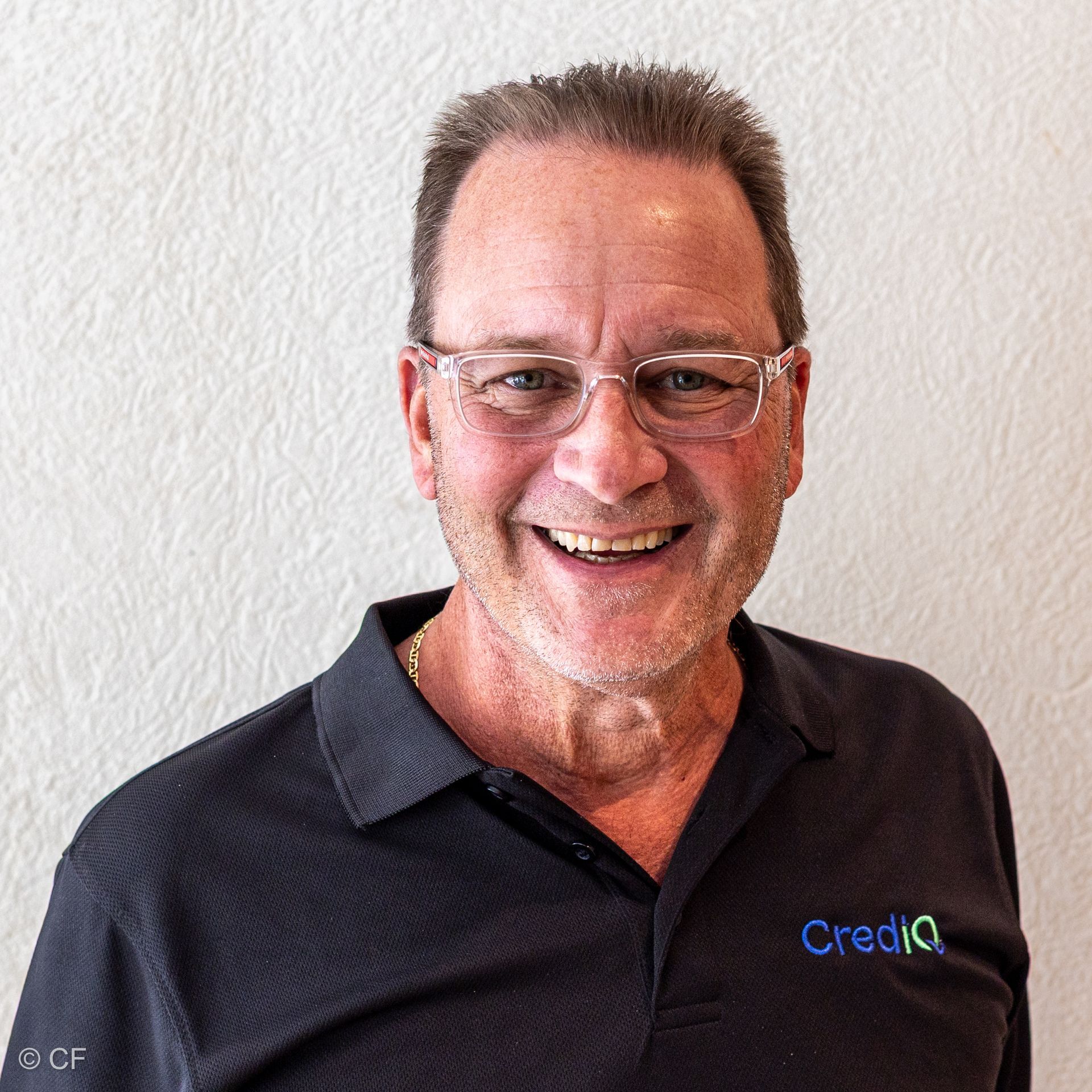 Thomas Pantin smiling wearing glasses and a dark polo shirt with a 