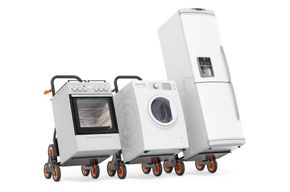 Appliances on moving dollies: oven, washing machine, refrigerator, white background.