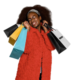 Woman with big hair and red coat smiles, holding colorful shopping bags.