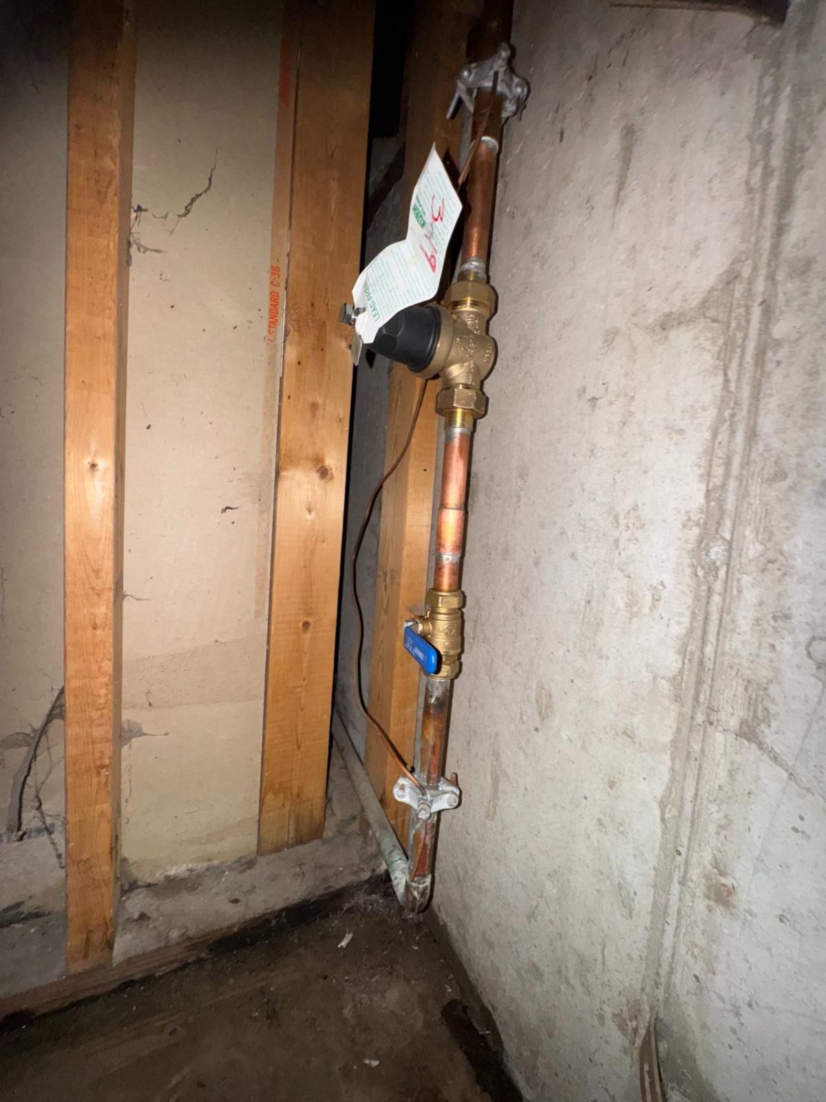 Exposed copper pipe with a shutoff valve in a unfinished wall corner