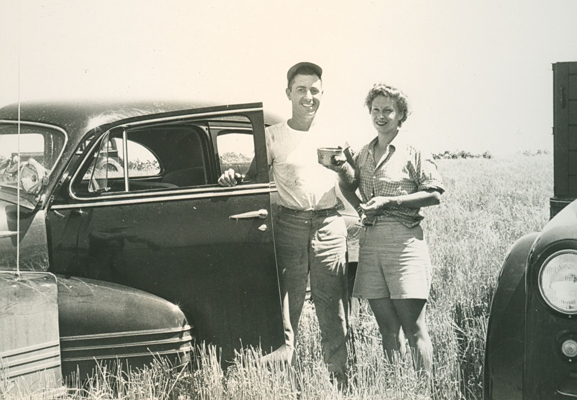 Harry and Anne Bingman in a field with their car enjoying a beverage, 1948. LandLogic Model Training for Community Members.