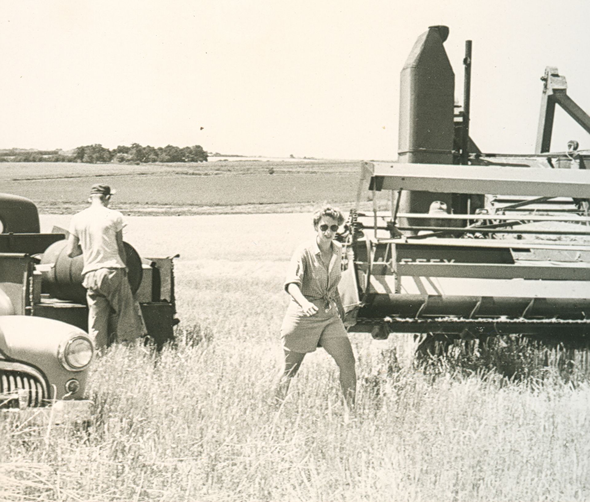 Famers harvesting a field with a combine and several trucks, 1948. LandLogic Model Training for Crisis Responders.