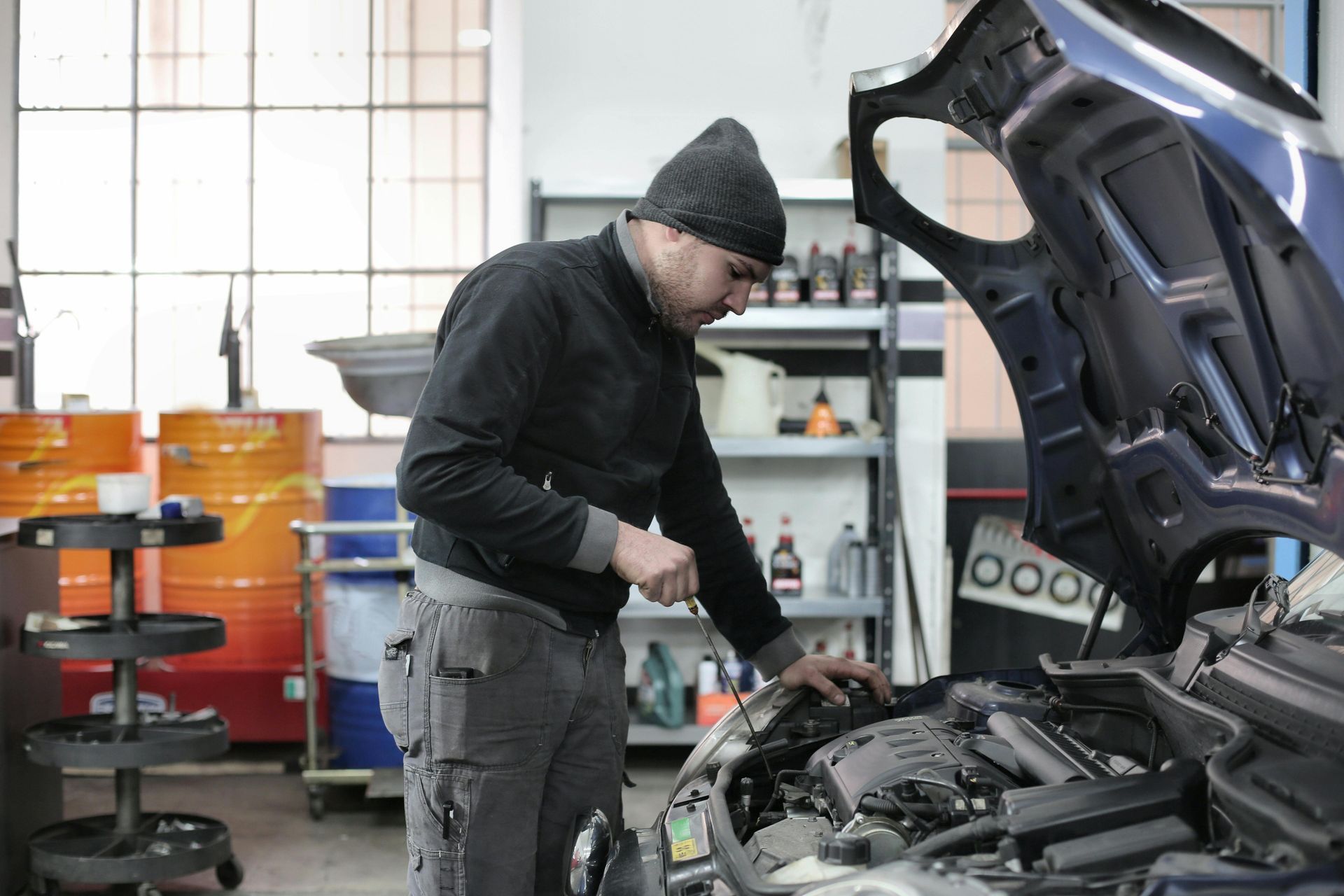 A man is working on the engine of a car in a garage.