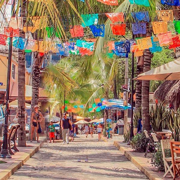 A street with palm trees and colorful flags hanging from them.