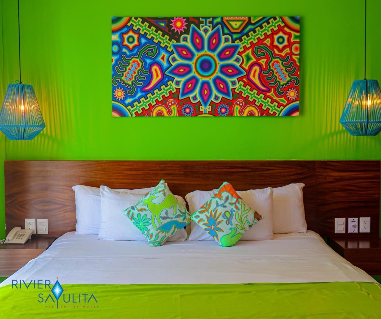 A bed with a colorful painting on the wall above it