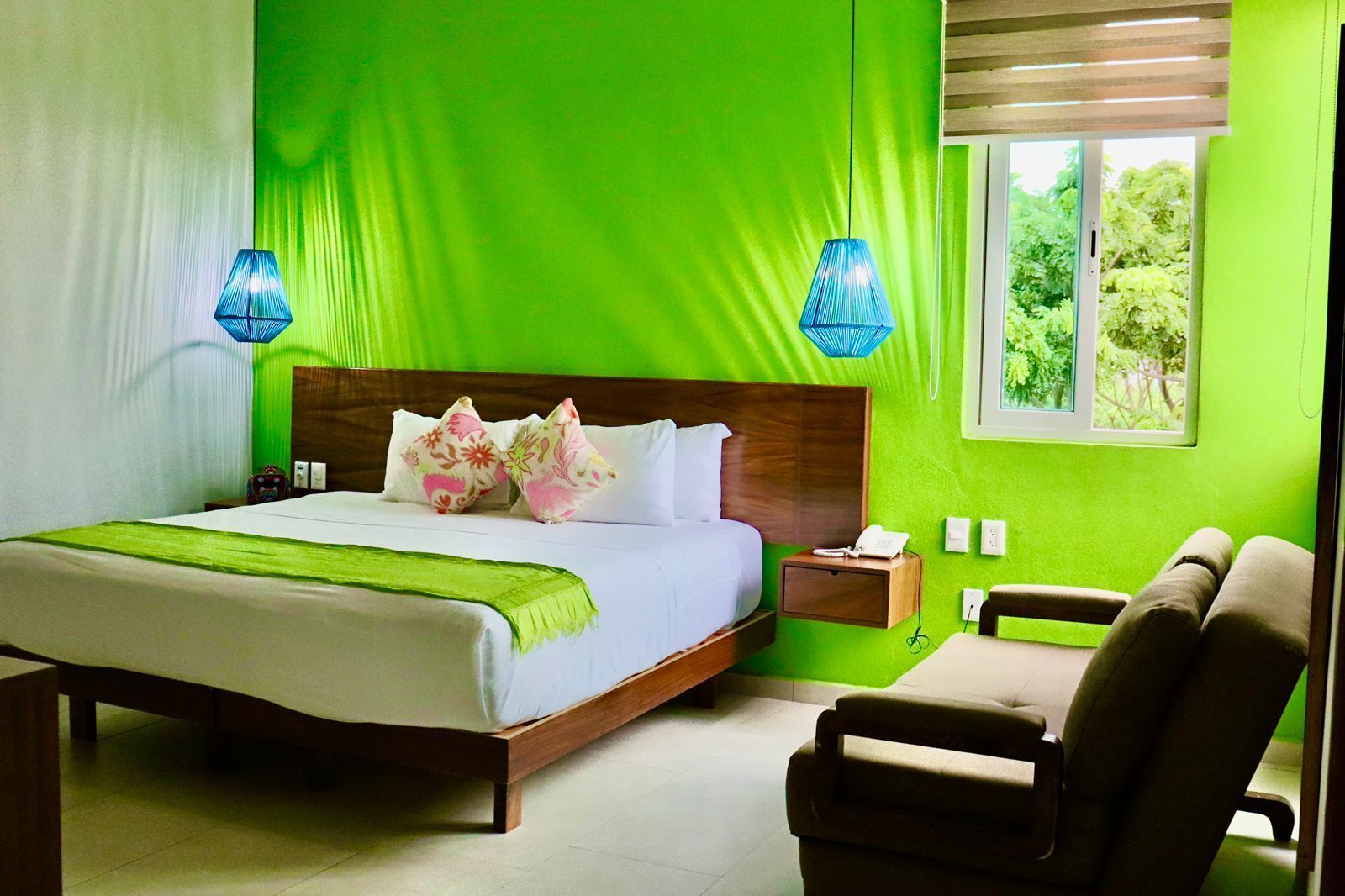A hotel room with a bed , couch , and green walls.