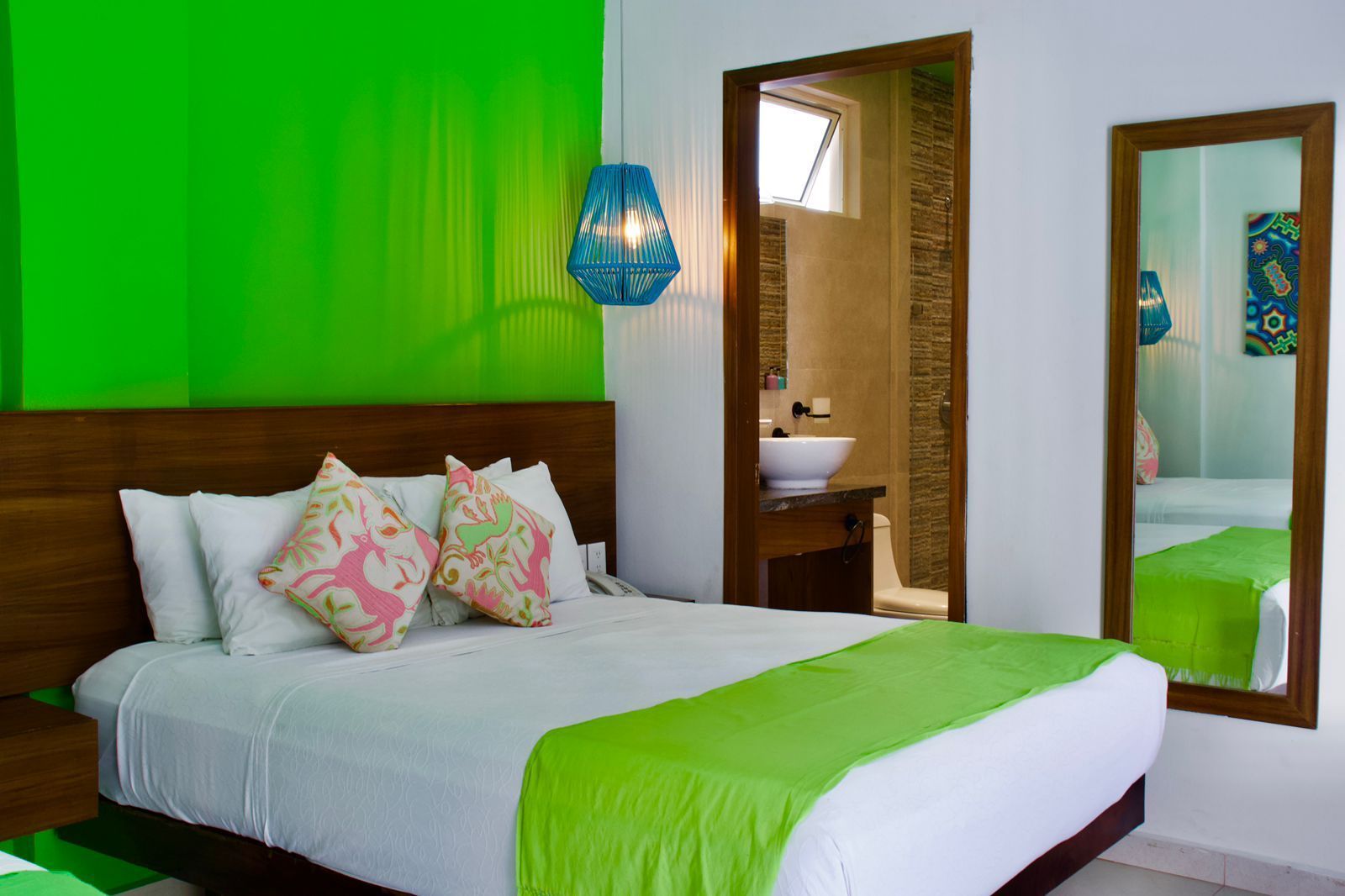 A hotel room with a bed , mirror and green walls.