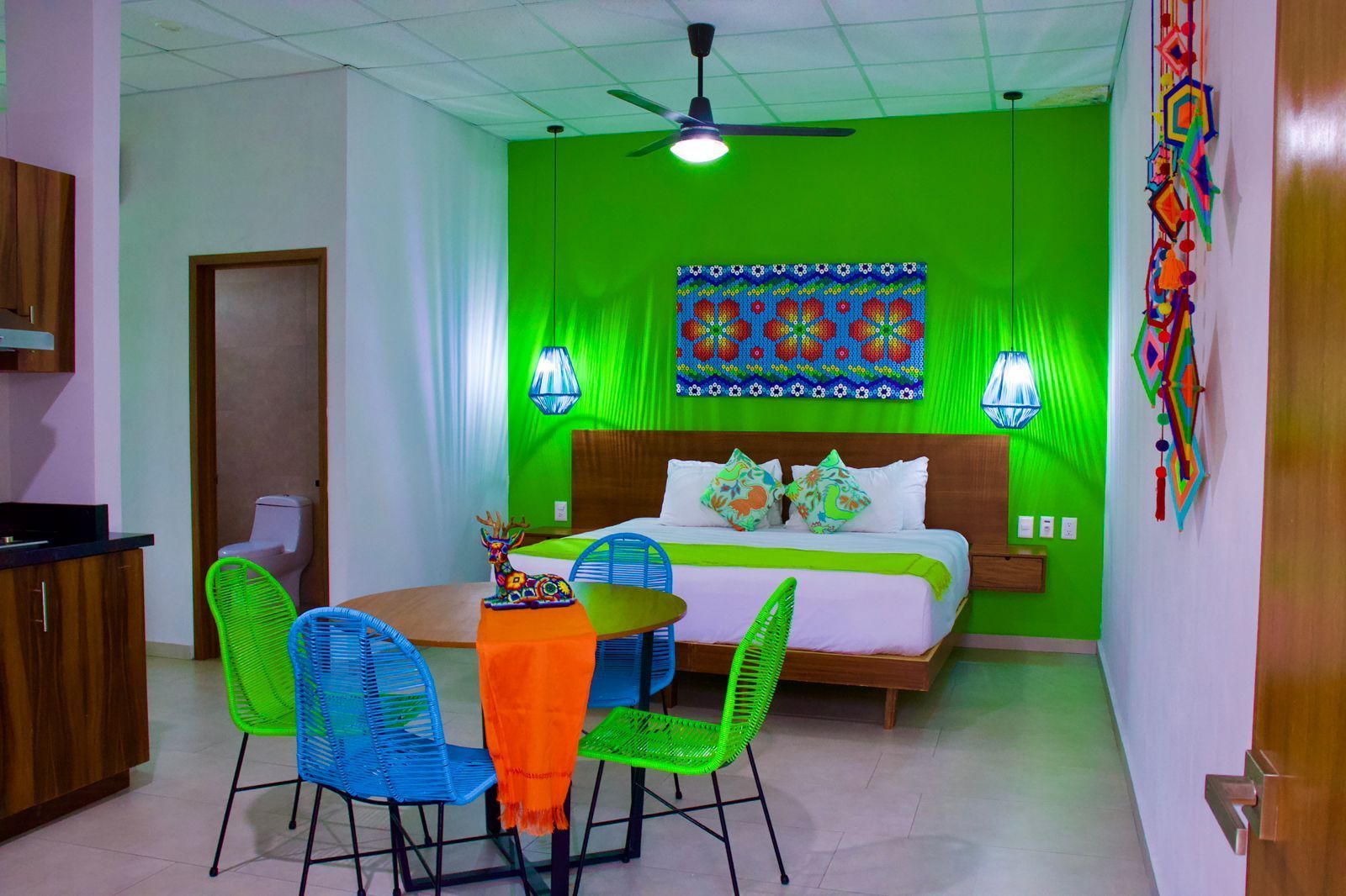 A hotel room with a bed , table , chairs and a ceiling fan.