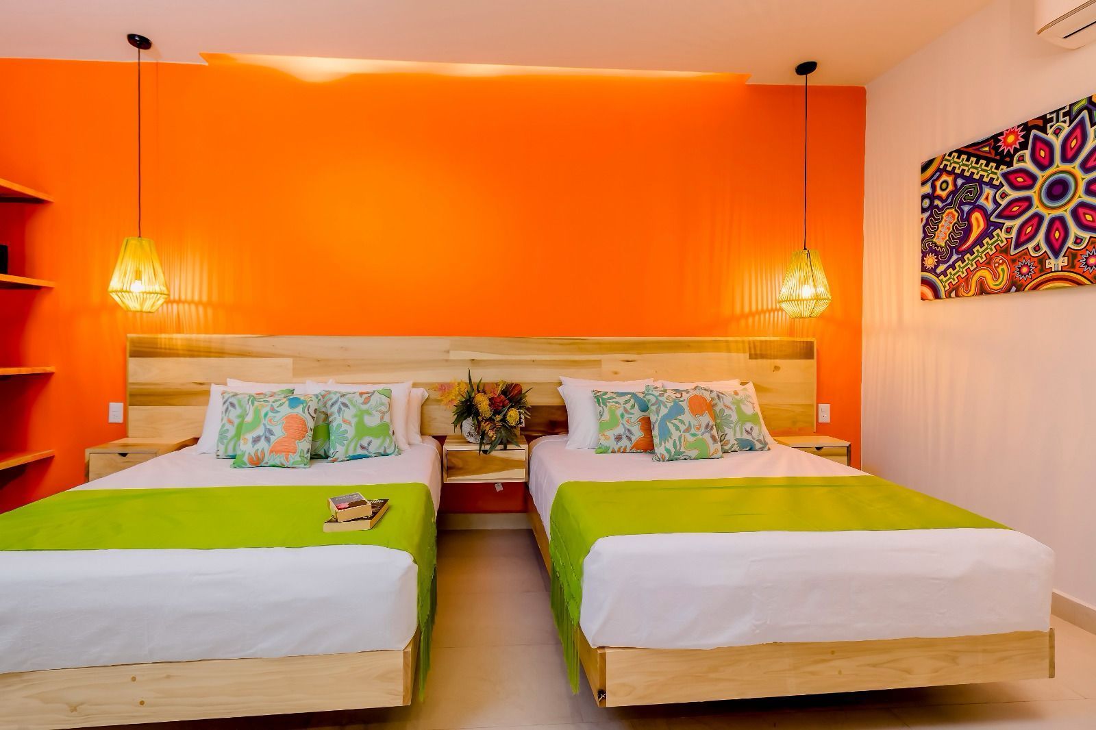 A hotel room with two beds and an orange wall.