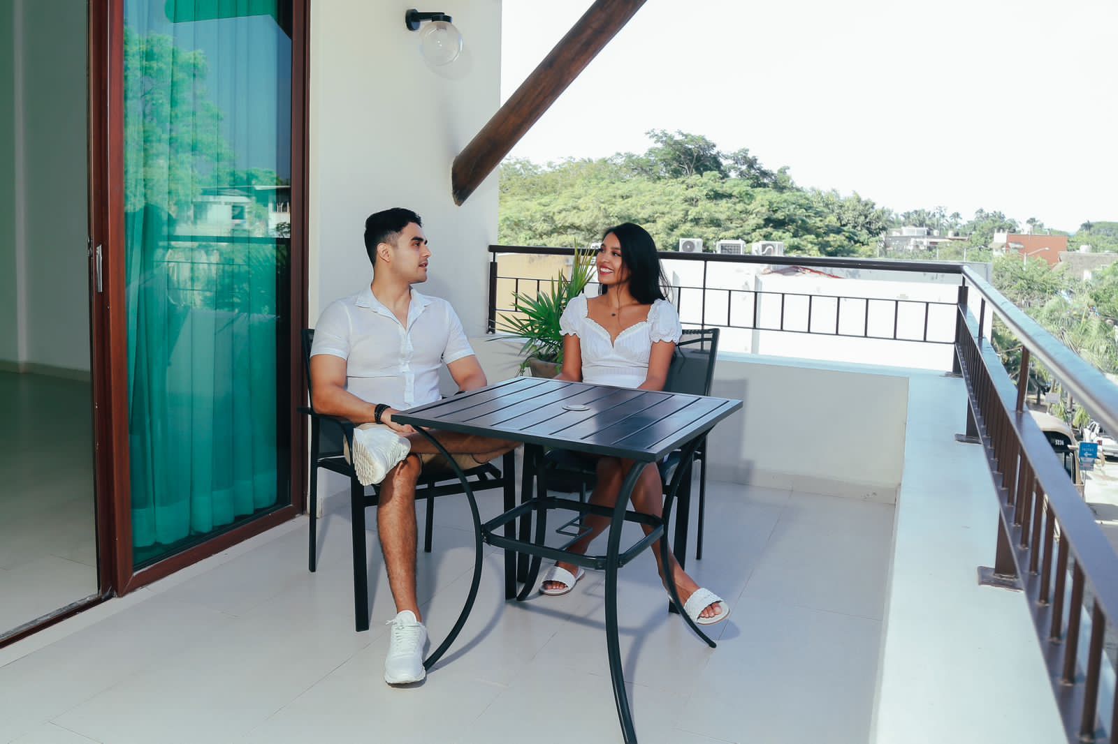 A man and a woman are sitting at a table on a balcony.