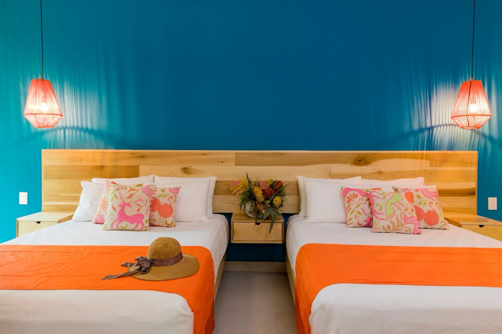 A hotel room with two beds and a blue wall.