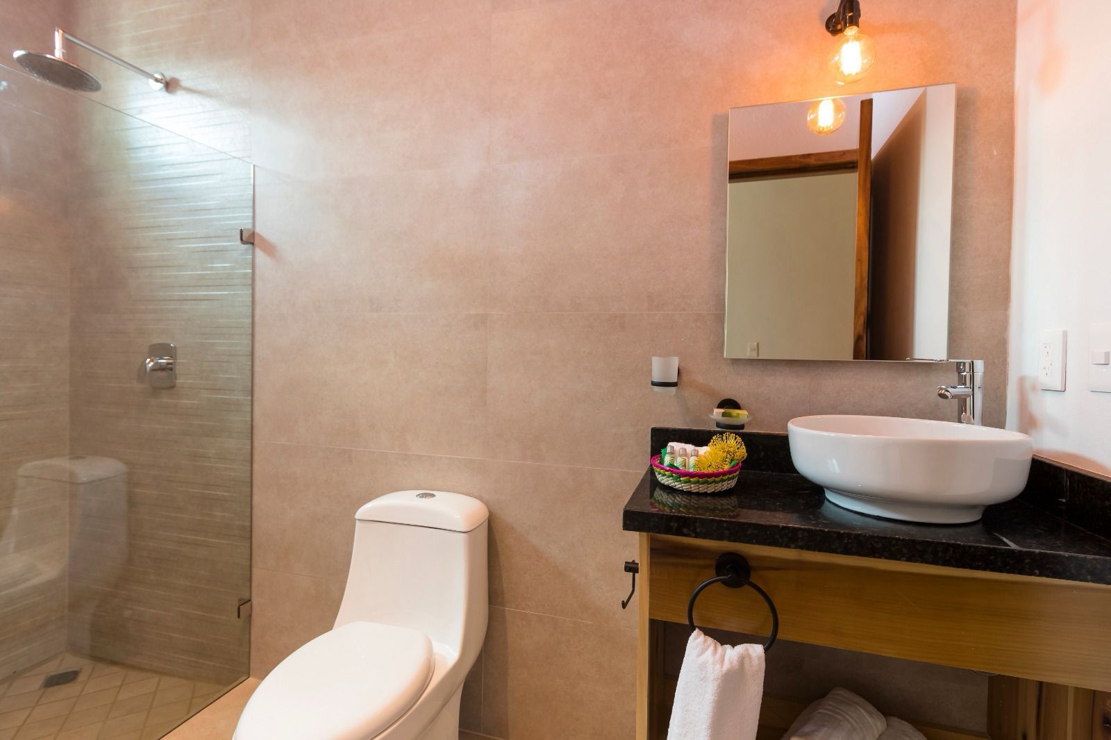 A bathroom with a toilet , sink , mirror and walk in shower.