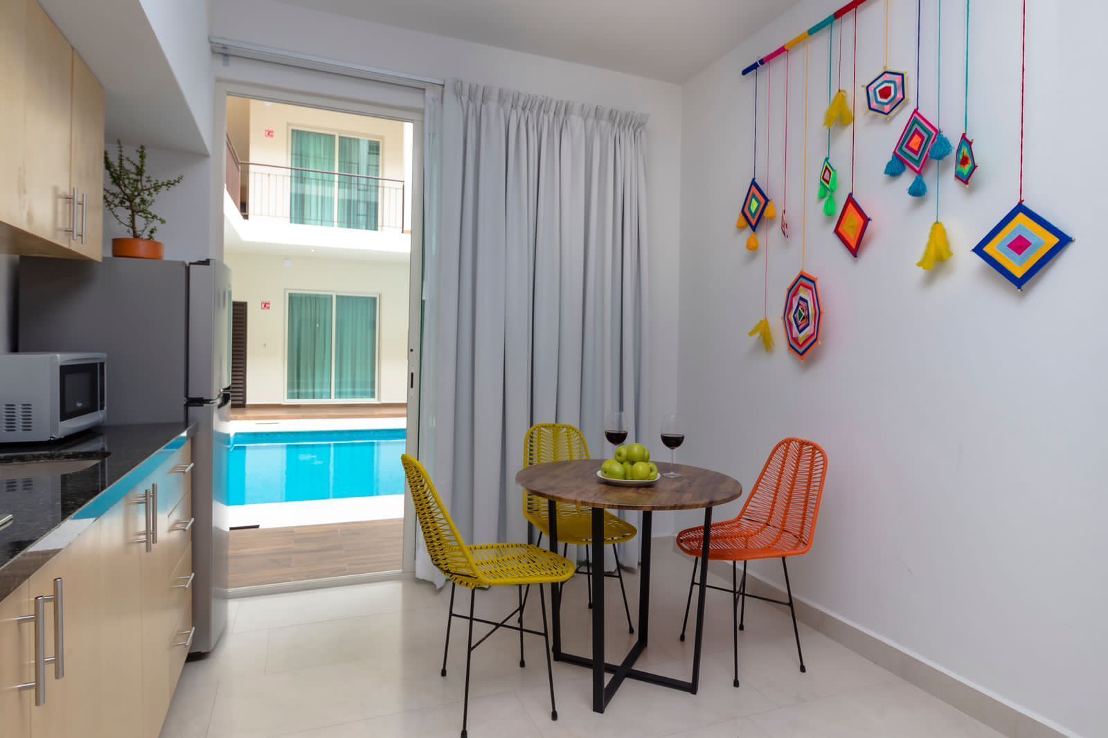 A kitchen with a table and chairs and a pool in the background.
