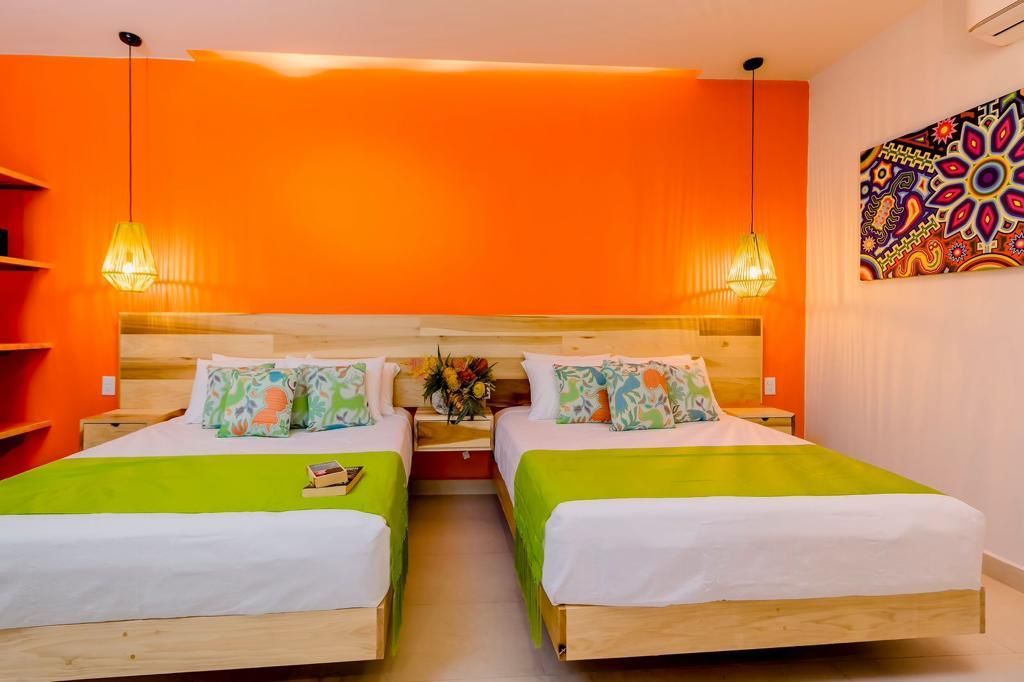 A hotel room with two beds and an orange wall.