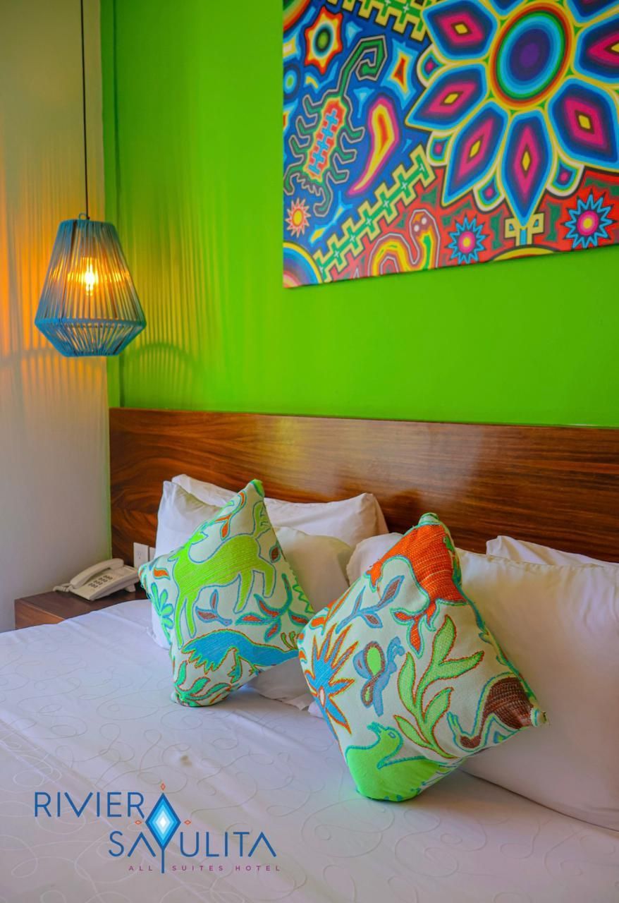 A bed with a colorful painting on the wall above it.
