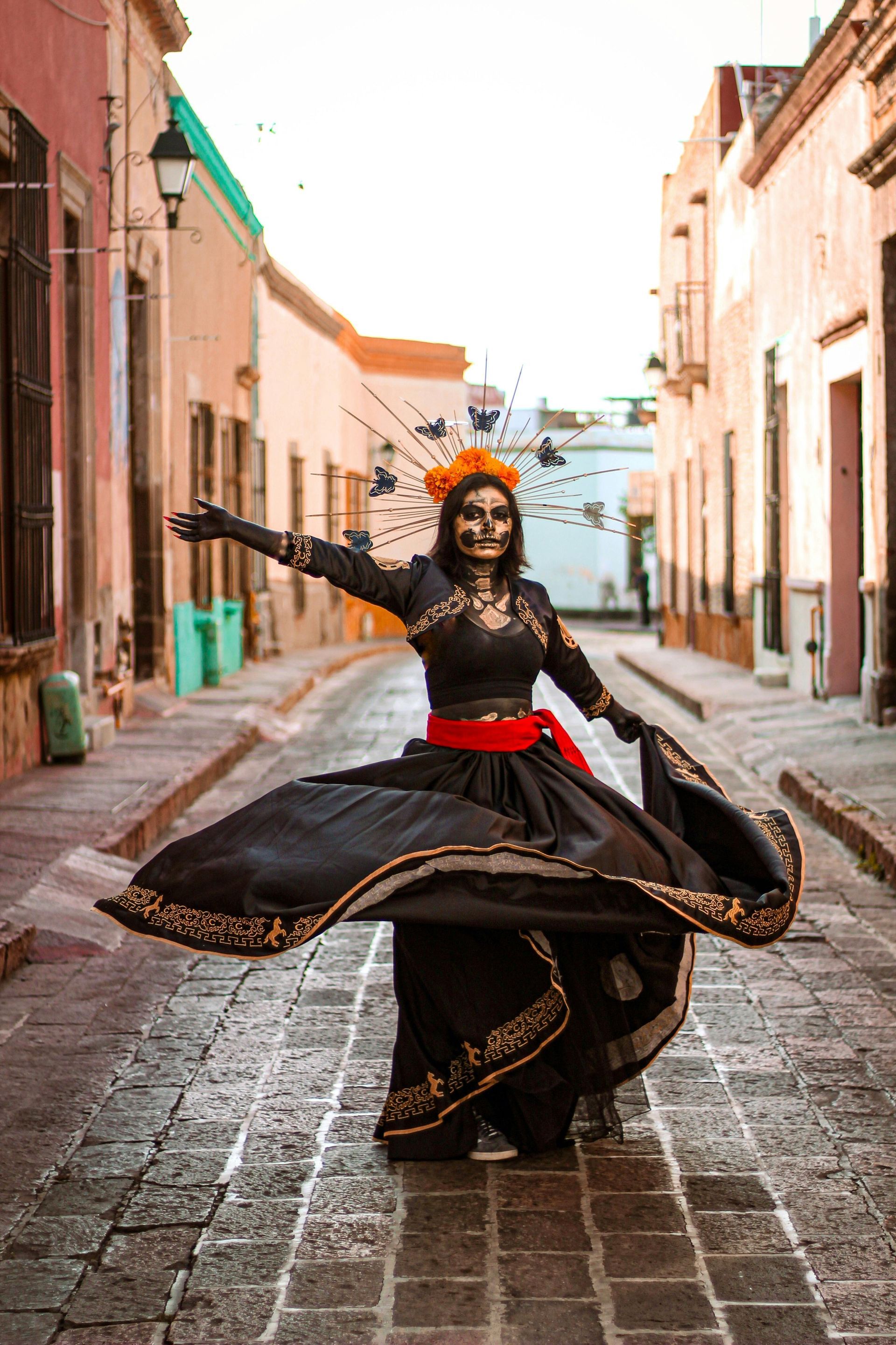 A woman dressed as a skeleton is dancing on a cobblestone street.