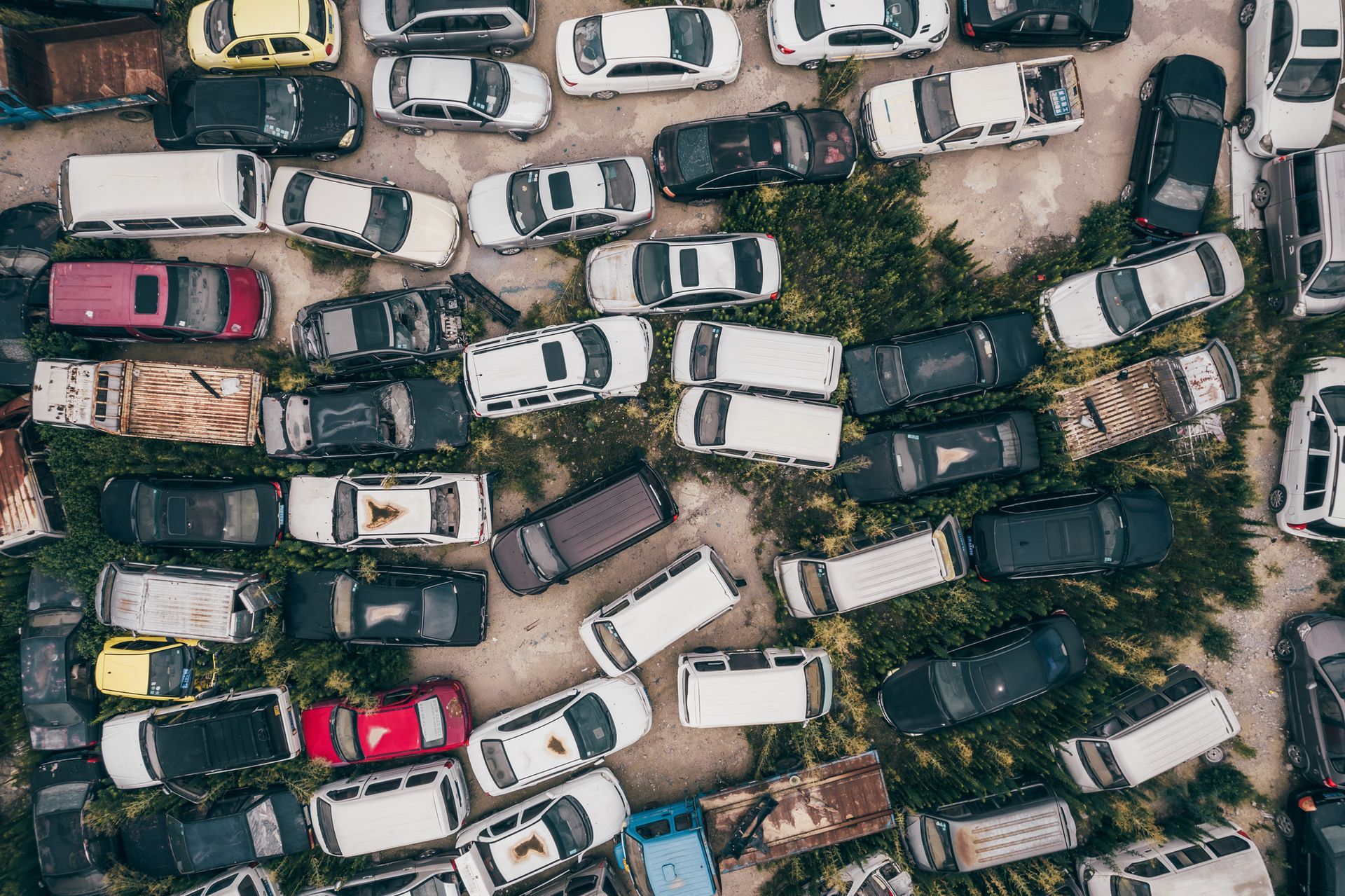 Overhead view of a junkyard filled with rows of old, discarded cars in various colors and conditions.