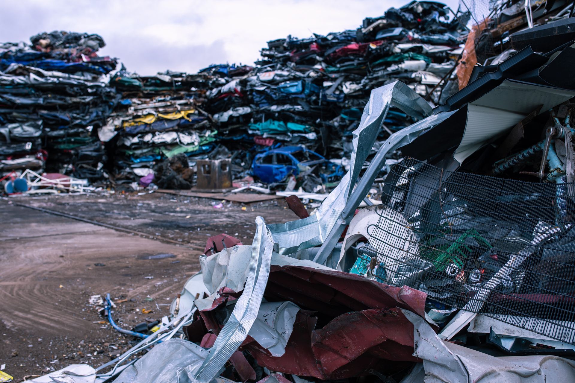 Scrap yard filled with stacked vehicles showing places that junk cars for recycling.