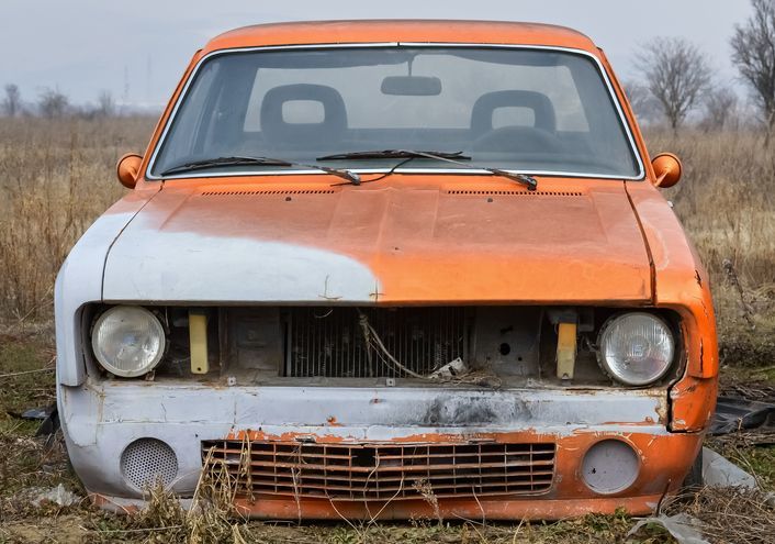 Close-up picture of the front part of an old abandoned car.