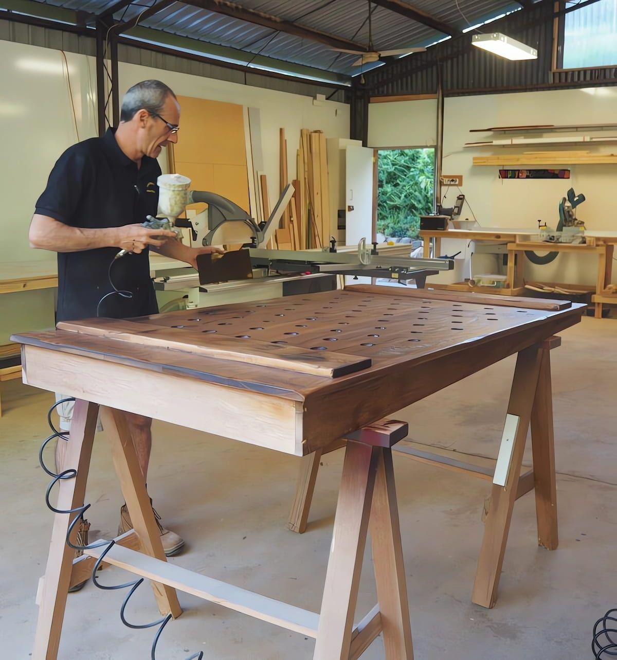 A Man Is Working On A Wooden Table In A Workshop — Simonetto'S Cabinets & Joinery in Noosa, QLD