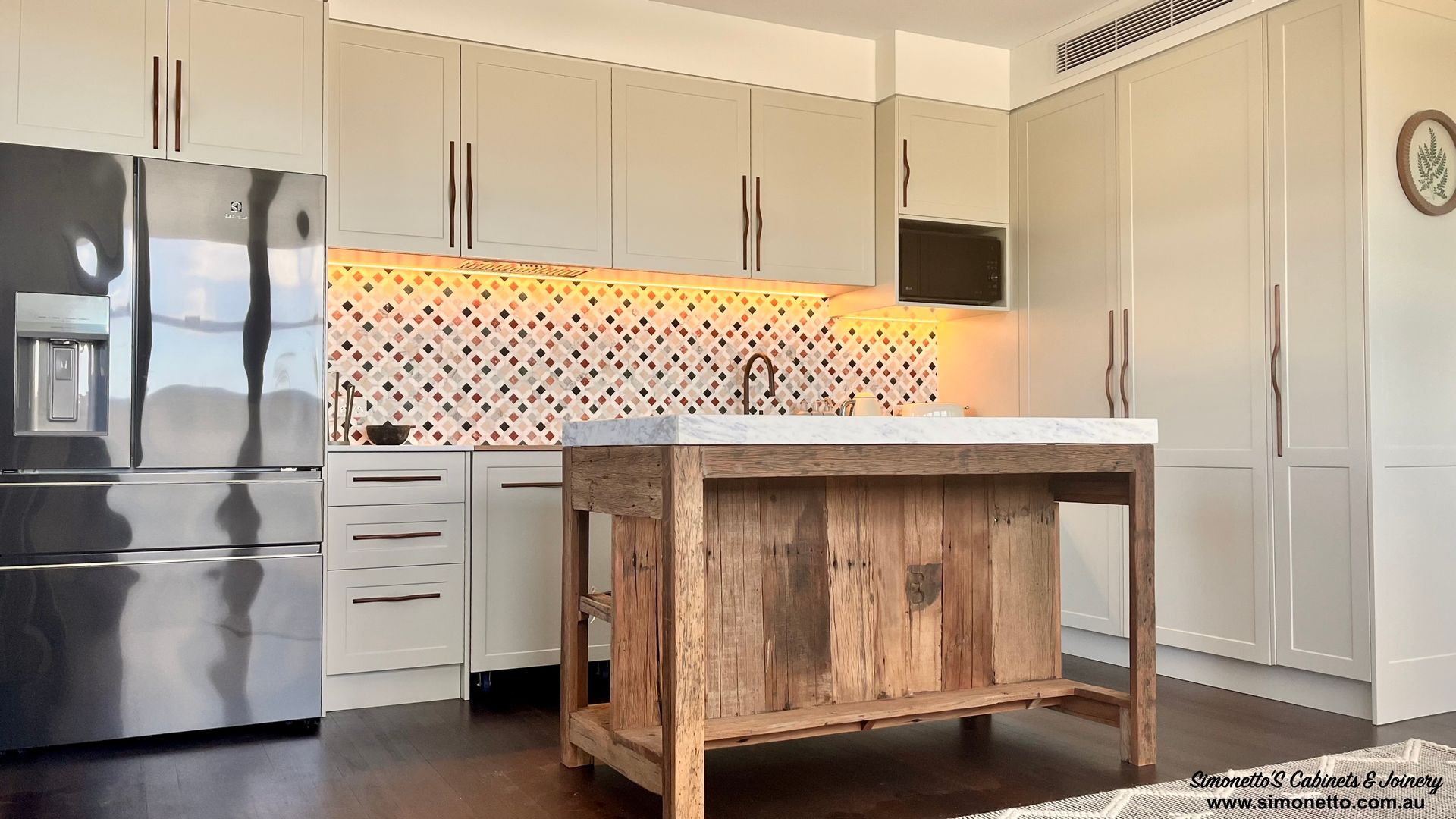 Modern kitchen with beige cabinets, wooden island, tiled backsplash, and stainless steel fridge.