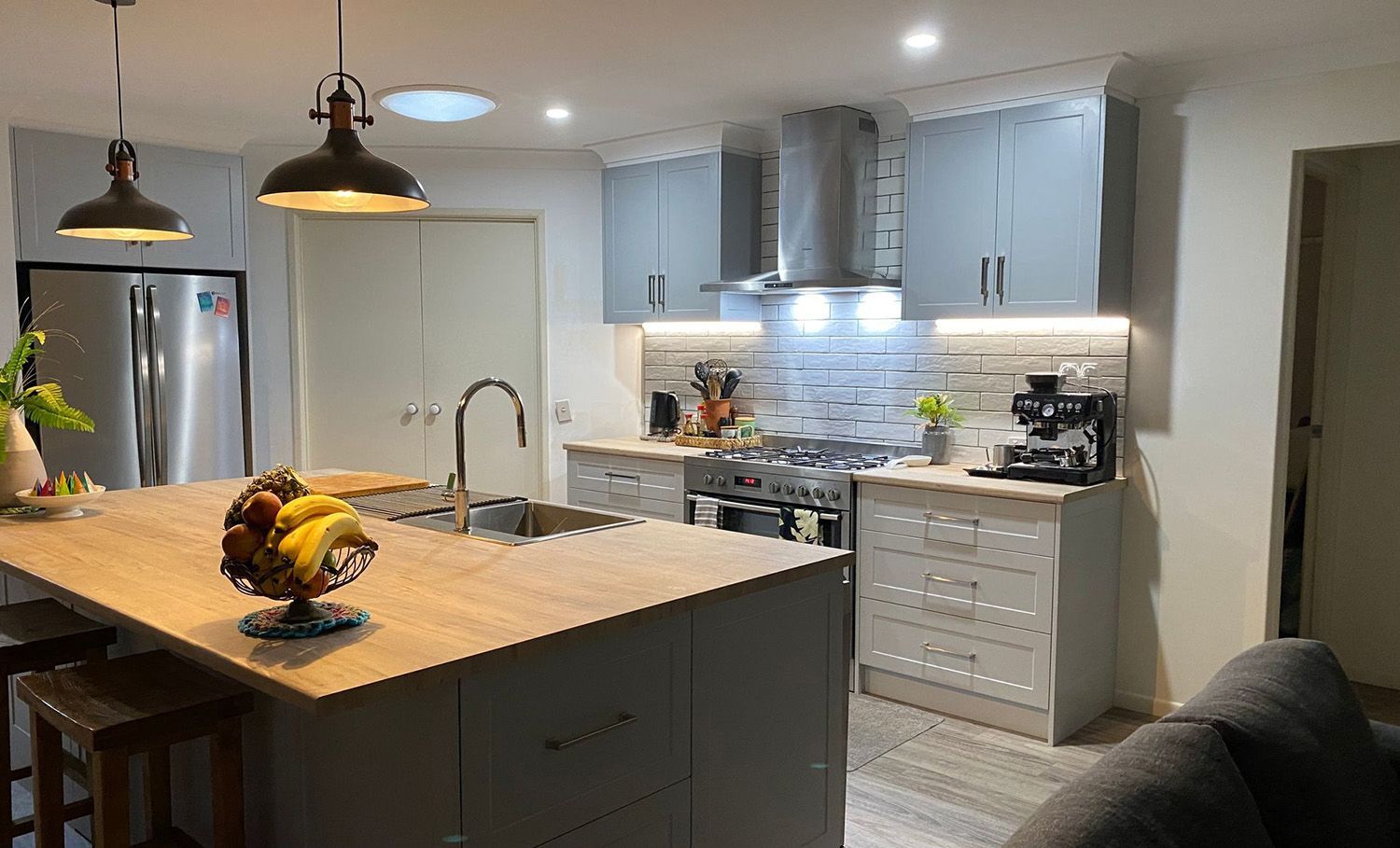 Modern kitchen with island, gray cabinets, stainless steel appliances, and wood countertops.
