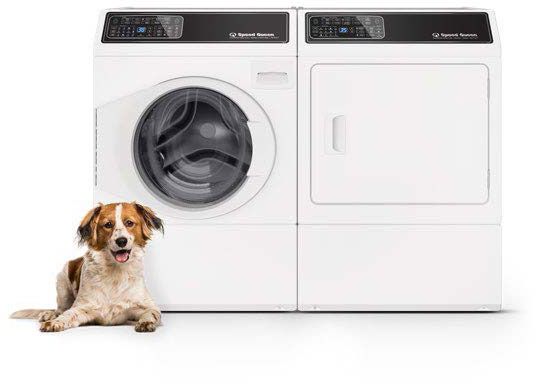 A dog is laying next to a front loading washing machine and dryer of the Speed Queen brand.