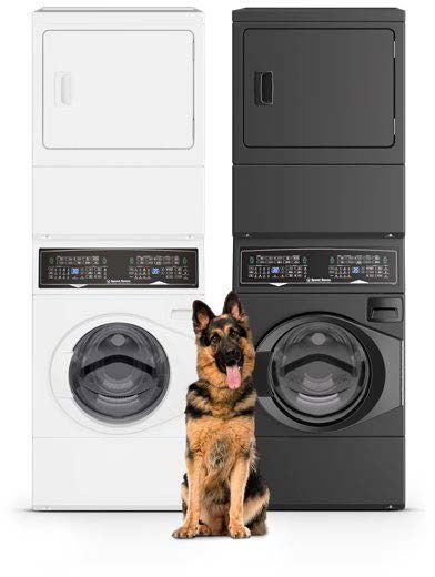 A german shepherd is sitting next to a pair of white and matte black Speed Queen stackable laundry units.