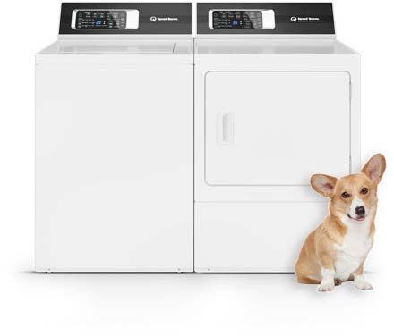 A corgi sitting next to a Speed Queen washer and dryer.
