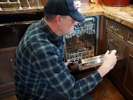 service tech making a repair to a residential miele dishwasher