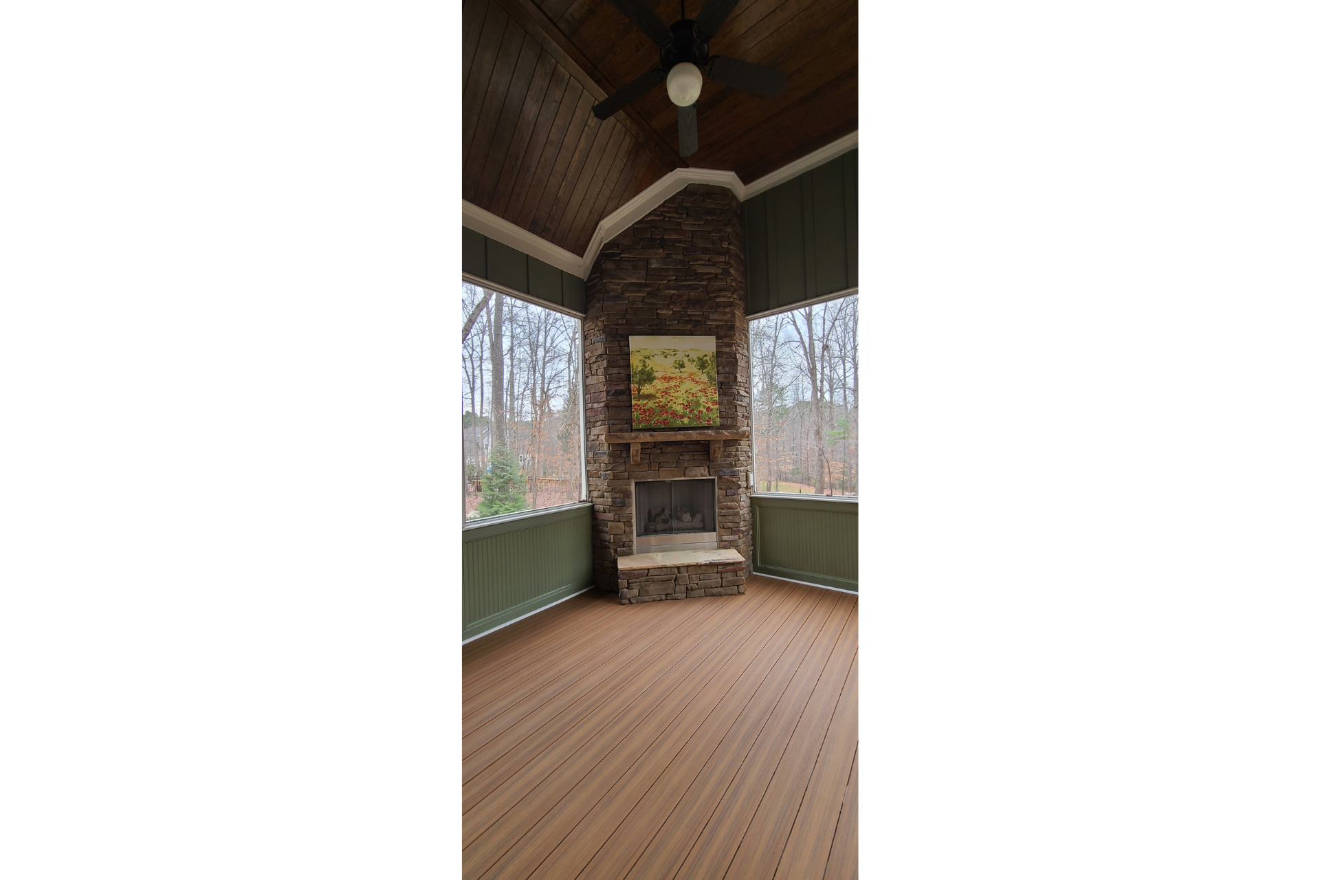 A screened-in porch with a stone fireplace, wood-plank flooring, a vaulted wood ceiling, and a ceiling fan.