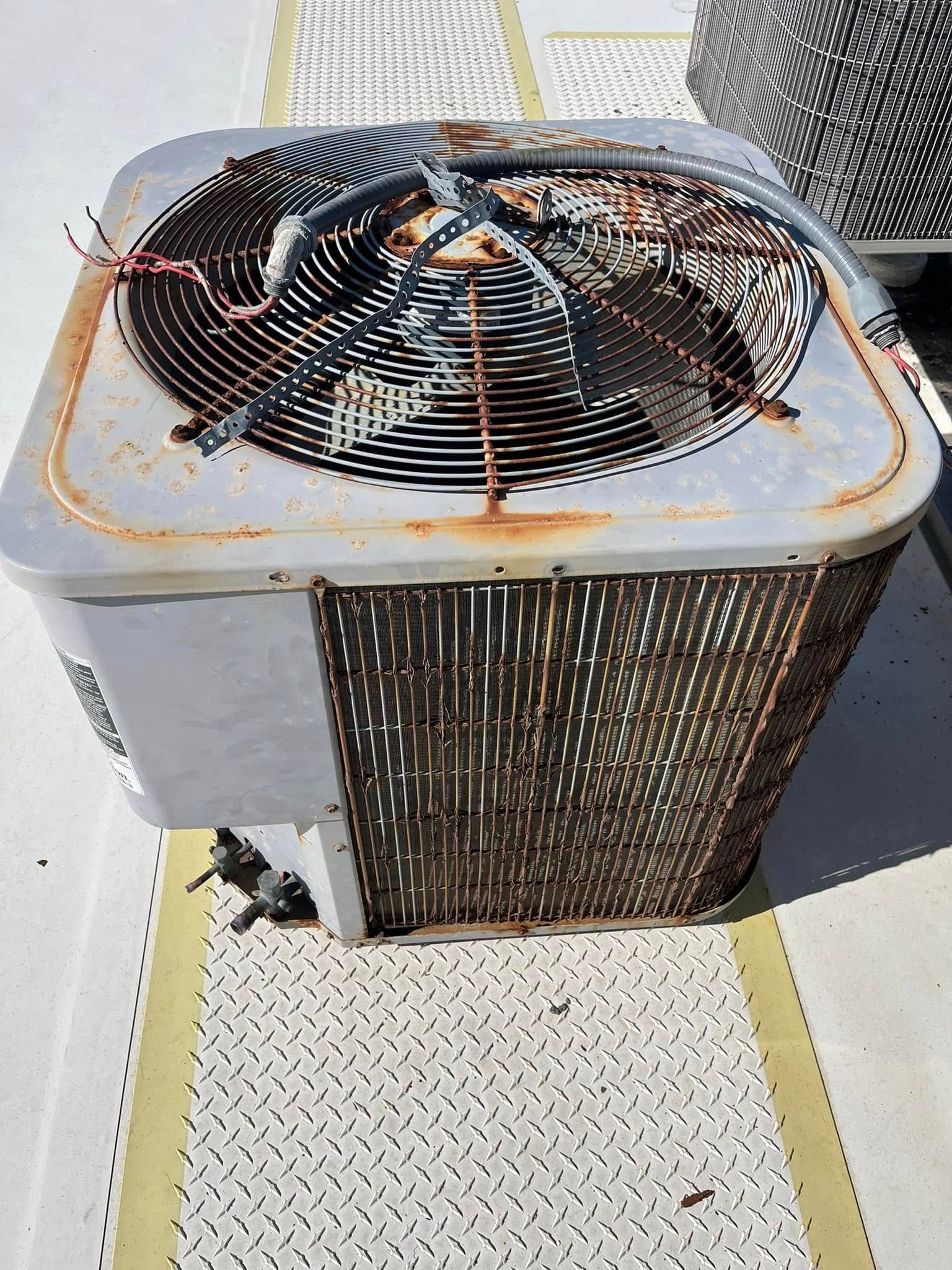 A rusty air conditioner is sitting on a roof.