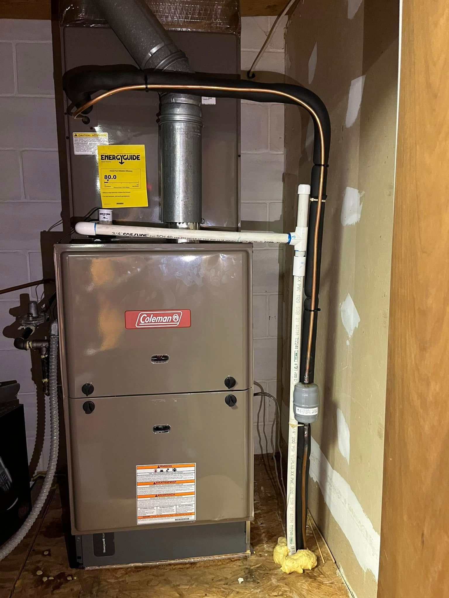 A furnace is sitting in a room next to a pipe.