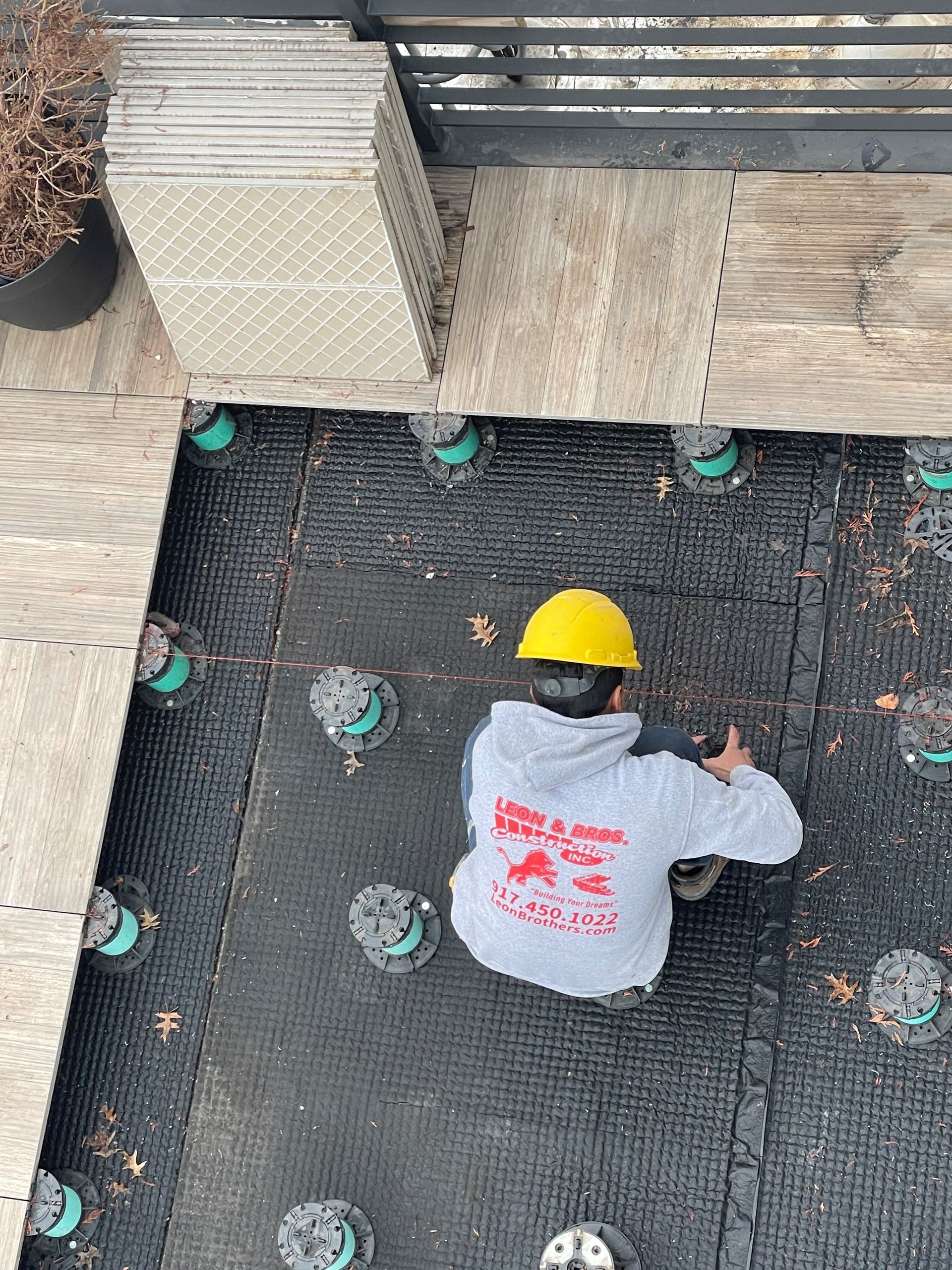 A Man Is Installing A Gutter On The Roof Of A House | Newark, NJ | Leon Brothers