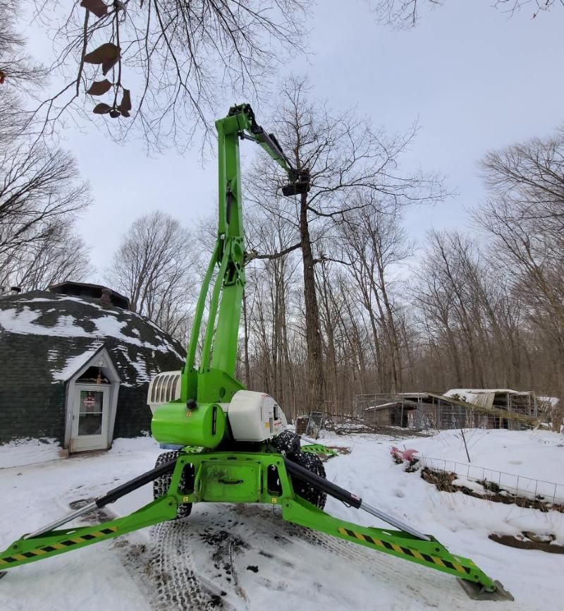 A green crane is standing in the snow in front of a dome