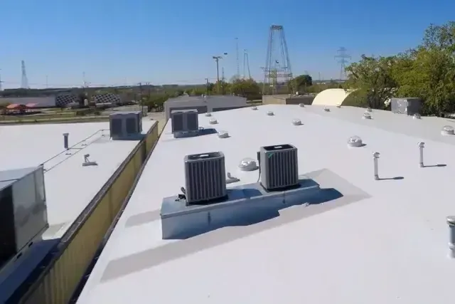 A white roof with two air conditioners on top of it