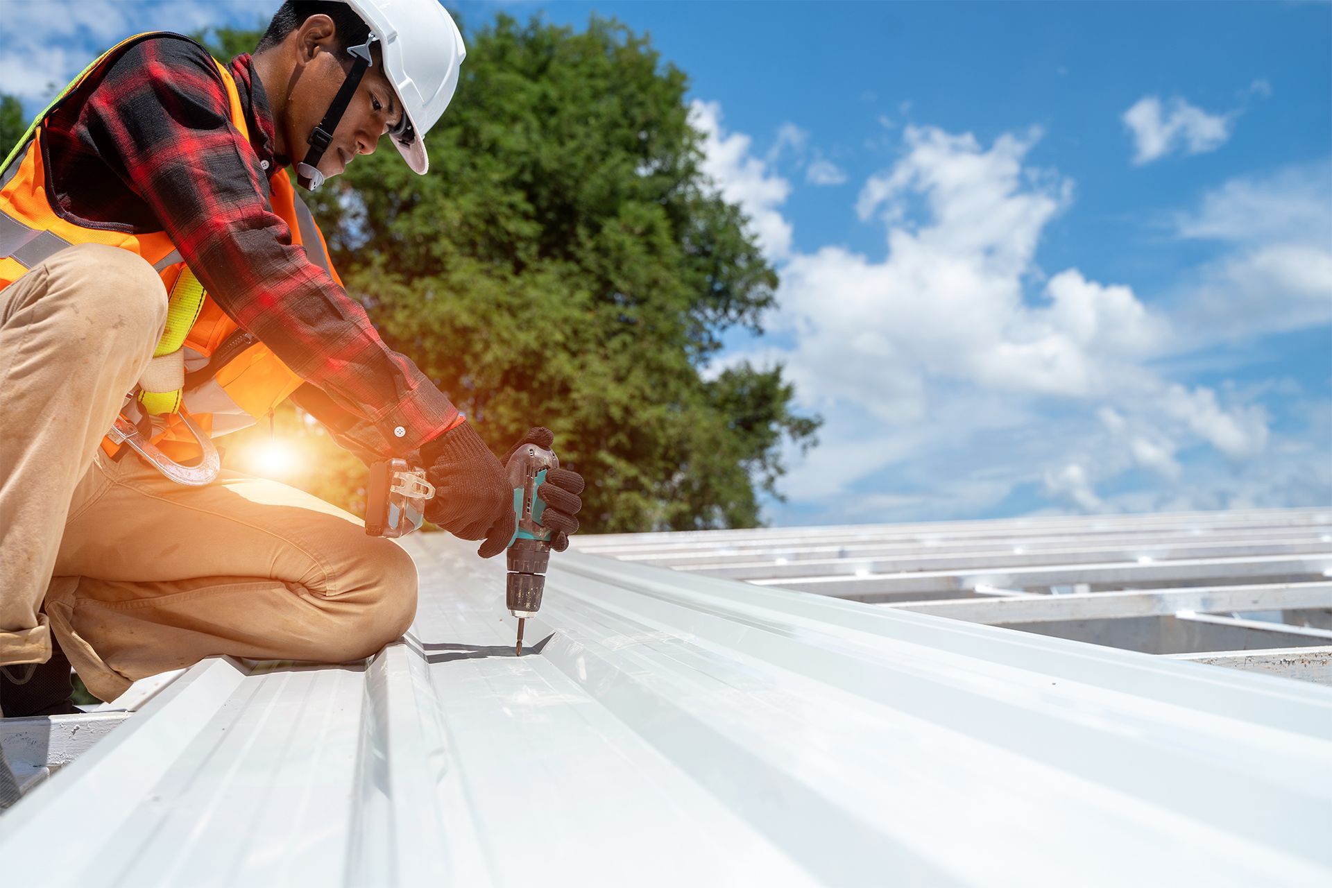 A construction worker is working on a roof with a drill.