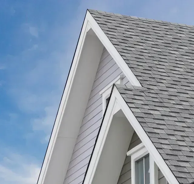 A white house with a gray roof and a blue sky in the background
