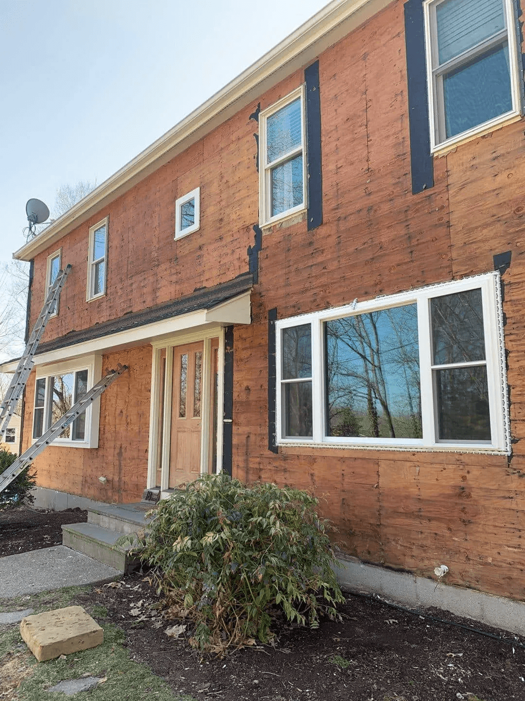 A brick house with a lot of windows and a ladder in front of it.